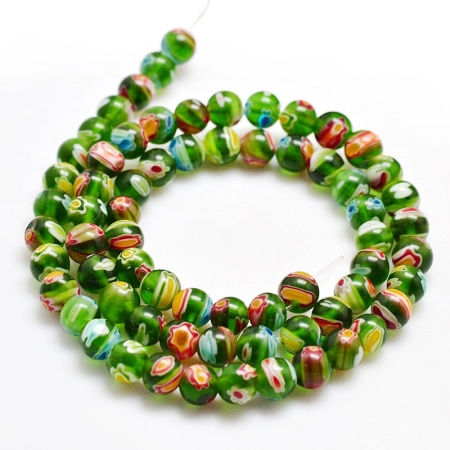 <p>Стеклянные бусины ручной работы, выполнены в технике миллефиори. Зелёные бусинки с разноцветными узорами. Оттенок может отличаться от фотографии и в разных поставках. Цена за низку около 65 бусин (низки формируются без проверки каждой бусины на дефекты).</p>