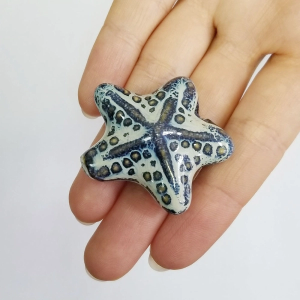 <p>Крупная эффектная керамическая бусина - морская звездочка ручной работы. Бусина покрыта глазурью светло-бежевого цвета с сине-голубыми и коричневыми узорами. Цвет может отличаться от фотографии. Бусины могут отличаться по форме и размеру, рисунок на каждой бусине уникален. Диаметр отверстия - около 2.5 мм. Цена за 1 бусину.</p><p>ВНИМАНИЕ: отверстие сделано не очень аккуратно, возможны небольшие сколы у отверстия.</p>
