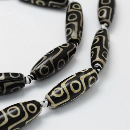 <p>Гладкие вытянутые бусины из натурального камня - тонированного агата, бусина Дзи Девятиглазая. Оттенок может отличаться от фотографии. Бусины могут немного отличаться по форме и размеру. В низке 5 бусин. Низки формируются производителем без проверки каждой бусины на дефекты и подбора по цвету и рисунку. Цена за низку.</p>